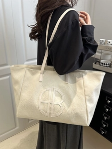 Cremefarbene Shopper-Tasche aus weichem Leder mit Logo-Prägung am Model präsentiert