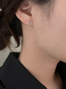 Detail shot of minimalist silver hollow heart stud earrings with linear drop bar on model