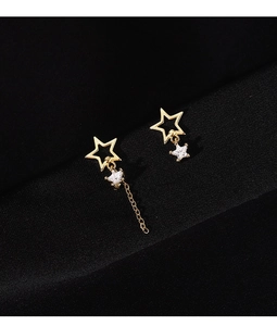 Gros plan de boucles d'oreilles étoiles dorées asymétriques avec pompons en cristal