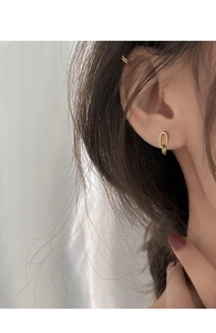 Close-up of a gold U-shaped earring and double ear cuff worn on a model's ear