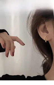 Close-up of minimalist golden oval hoop earrings on model with elegant jewelry details