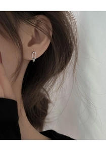 Close-up of minimalist silver geometric oval hoop earrings worn by a model in profile