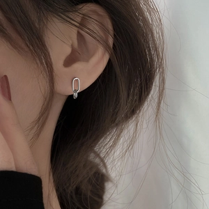 Minimalist silver geometric oval hoop earrings worn by a model in a close-up profile view