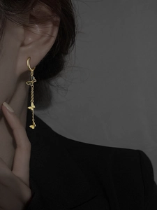 Gros plan de boucles d'oreilles papillon dorées à pampilles portées par un mannequin