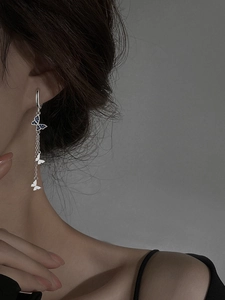 Boucles d'oreilles papillon à pampilles avec cristaux bleus portées par un mannequin