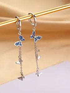 Détail de boucles d'oreilles papillon en argent avec pierres bleues sur satin élégant