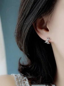 Gros plan de boucles d'oreilles nœud en argent S925 avec zircons blancs sur le modèle