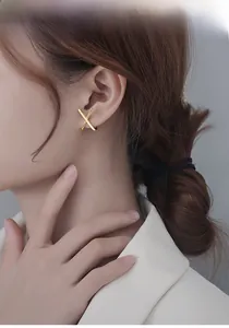 Close-up of gold-plated X-shaped cross earrings with sparkling pavé cubic zirconia details