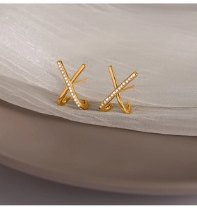 Close-up of gold-plated X-shaped earrings with micro-paved white zircons and polished finish