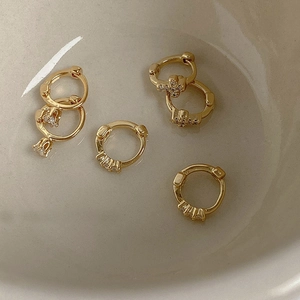 Vista macro de pendientes dorados con cruz de circonitas y colgantes de gota