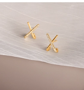 Close-up of gold S925 silver X-shaped earrings with fine white zircon pavé details
