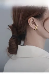 Macro detail of elegant crisscross X-shaped gold earrings with sparkling pave zircon stones