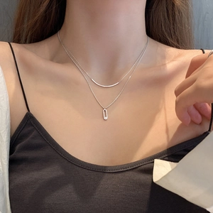 Close-up of double-layer S925 silver necklace featuring curved bar and oval rhinestone pendants