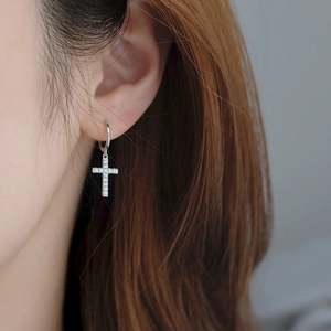 Boucle d'oreille créole en argent avec croix en zircone portée par un mannequin