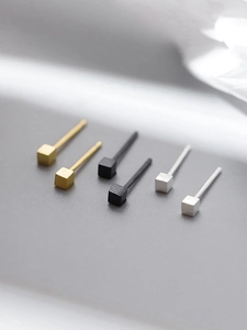 Macro shot of minimalist S925 silver cube stud earrings in gold, black, and silver finishes