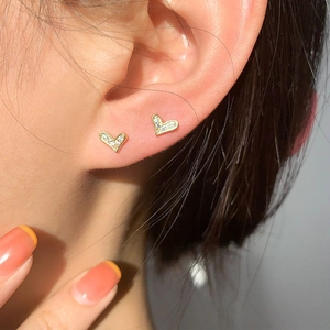 Elegant gold heart earrings with white zircons shown on model for a modern minimalist style
