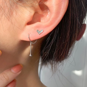 Macro shot of silver heart stud and asymmetric drop chain earrings with zircons