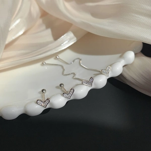 Macro shot of S925 silver heart stud earrings and long chain ear threaders with zircon stones
