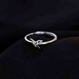 Elegante zilveren origami kraanvogel ring met zirkonia op zwarte textiel achtergrond