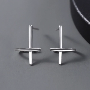 Macro shot of polished silver cross earrings with a sleek minimalist metallic finish