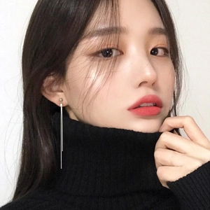 Detail view of long silver tassel earrings worn with a black turtleneck sweater