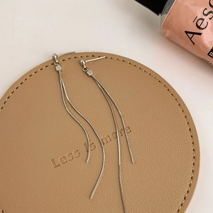 Macro detail of silver long tassel earrings with sleek snake chains and polished beads
