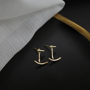 Gros plan de boucles d'oreilles minimalistes en or sur un fond de tissu élégant
