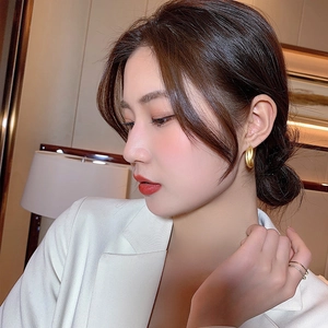 Elegant matte gold twisted hoop earrings worn by a model in a white business suit