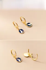 Detail view of gold earrings with blue enamel cat silhouette charms and hinge mechanism