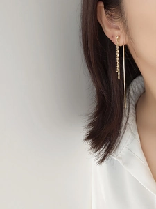 Close-up of elegant long gold tassel chain earrings worn on a female model