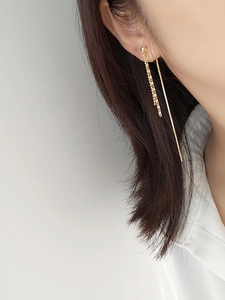 Close-up of elegant long tassel clip-on earrings in gold finish on a model's ear