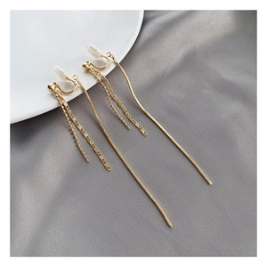 Detail of gold tassel clip-on earrings with U-shaped resin pads on grey silk background