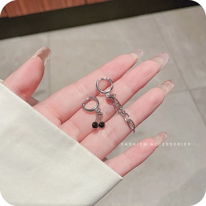 Asymmetric silver heart cherry earrings featuring unique black pendant on hand