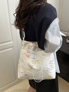 White quilted canvas tote bag with colorful wave embroidery and drawstring closure