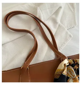 Detail of brown leather tote bag handle decorated with a vintage paisley silk scarf