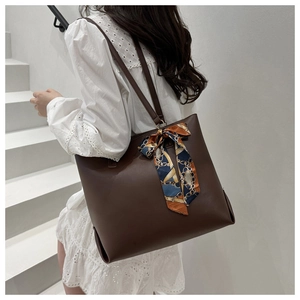 Detail der dunkelbraunen Leder-Shopper mit dekorativem bedrucktem Seidenschal am Tragegriff