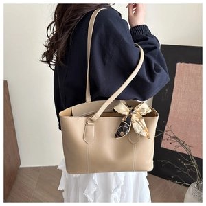 Detail of beige tote bag with white contrast stitching and a printed silk scarf handle