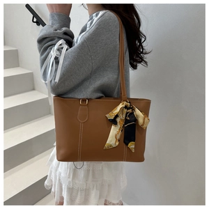 Brown tote bag detail with decorative floral silk scarf handle and contrast stitching