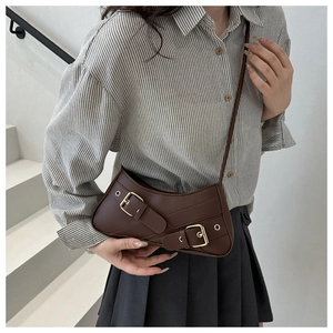 Detail of vintage brown asymmetrical shoulder bag with double belt buckles and gold hardware