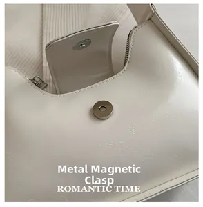 Detailed view of silver magnetic hardware buckle on creamy beige faux leather baguette bag