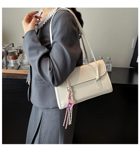 Sac à bandoulière blanc crème en similicuir avec breloque porté par un mannequin