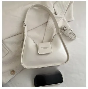 Detail view of small beige square bag showing the adjustable strap and phone size comparison