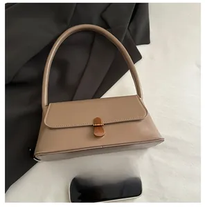 Flat lay of vintage beige square handbag with bronze buckle and shoulder strap
