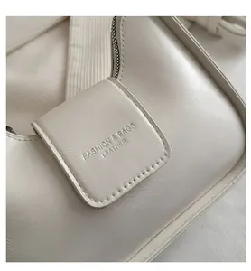 Macro shot of off-white leather shoulder bag with embossed fashion logo and flap detail