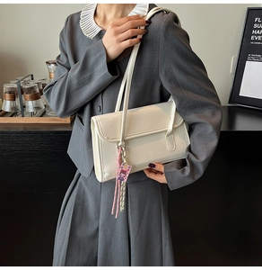 Sac bandoulière minimaliste en cuir blanc avec cordon tressé rose et breloque décorative