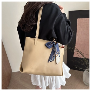 Nahaufnahme einer beigen Shopper-Tasche mit Seidenschal-Detail und langen Schulterriemen