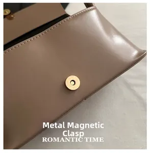 Close-up of magnetic snap closure on vintage brown leather handbag with gold hardware