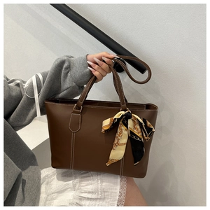 Brown tote bag detail with white contrast stitching and silk scarf on handle