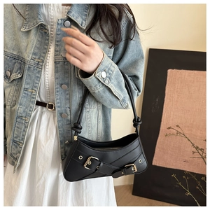 Detail of black underarm bag with decorative metal buckle straps and knotted shoulder strap
