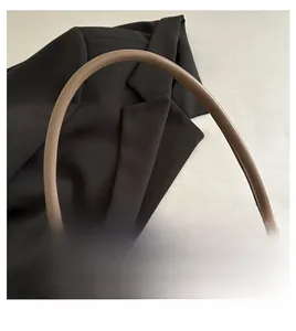 Close-up of brown leather top handle and fine stitching on a vintage square bag